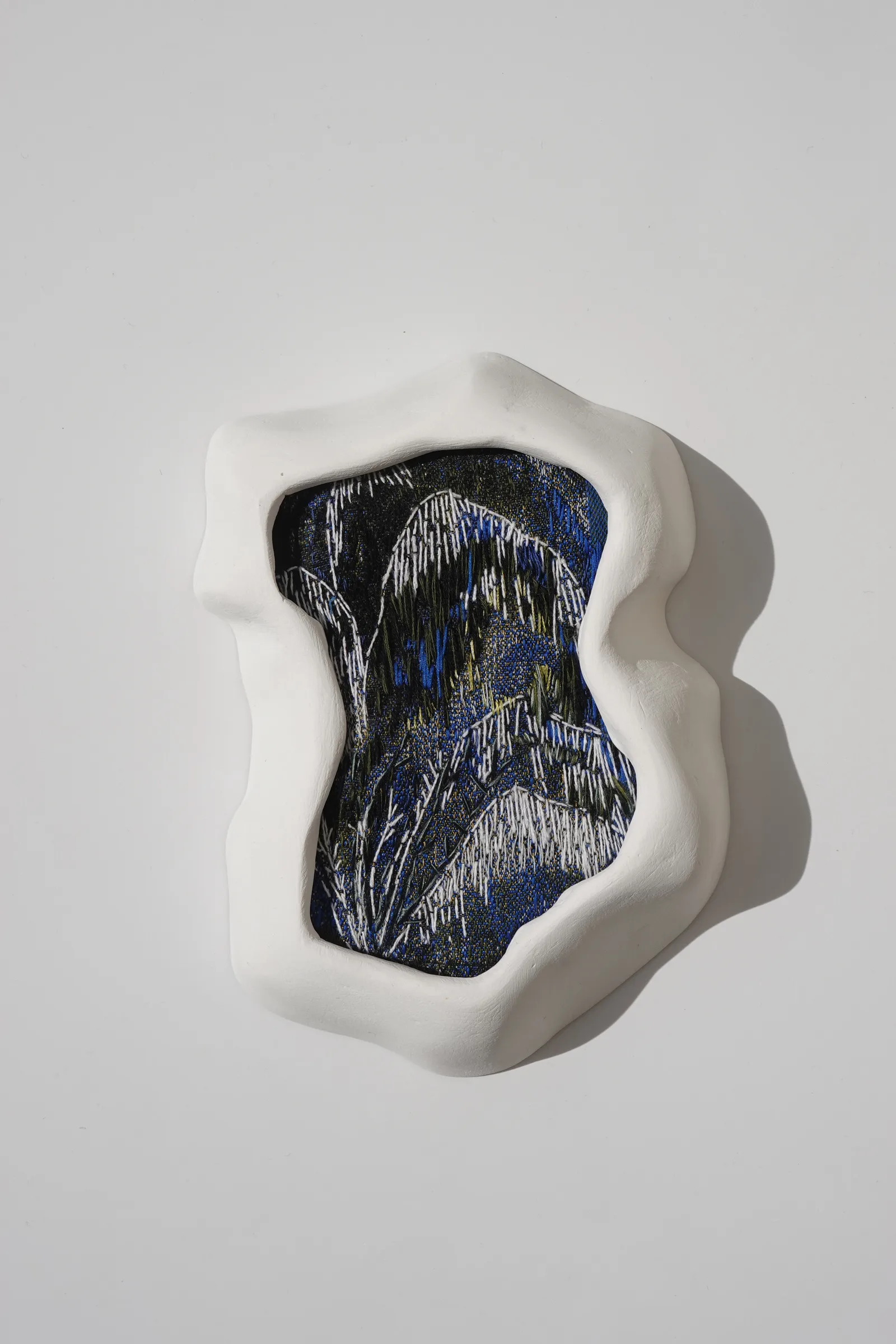 Memories 05, textil bordado en un marco de yeso blanco — vista de la obra