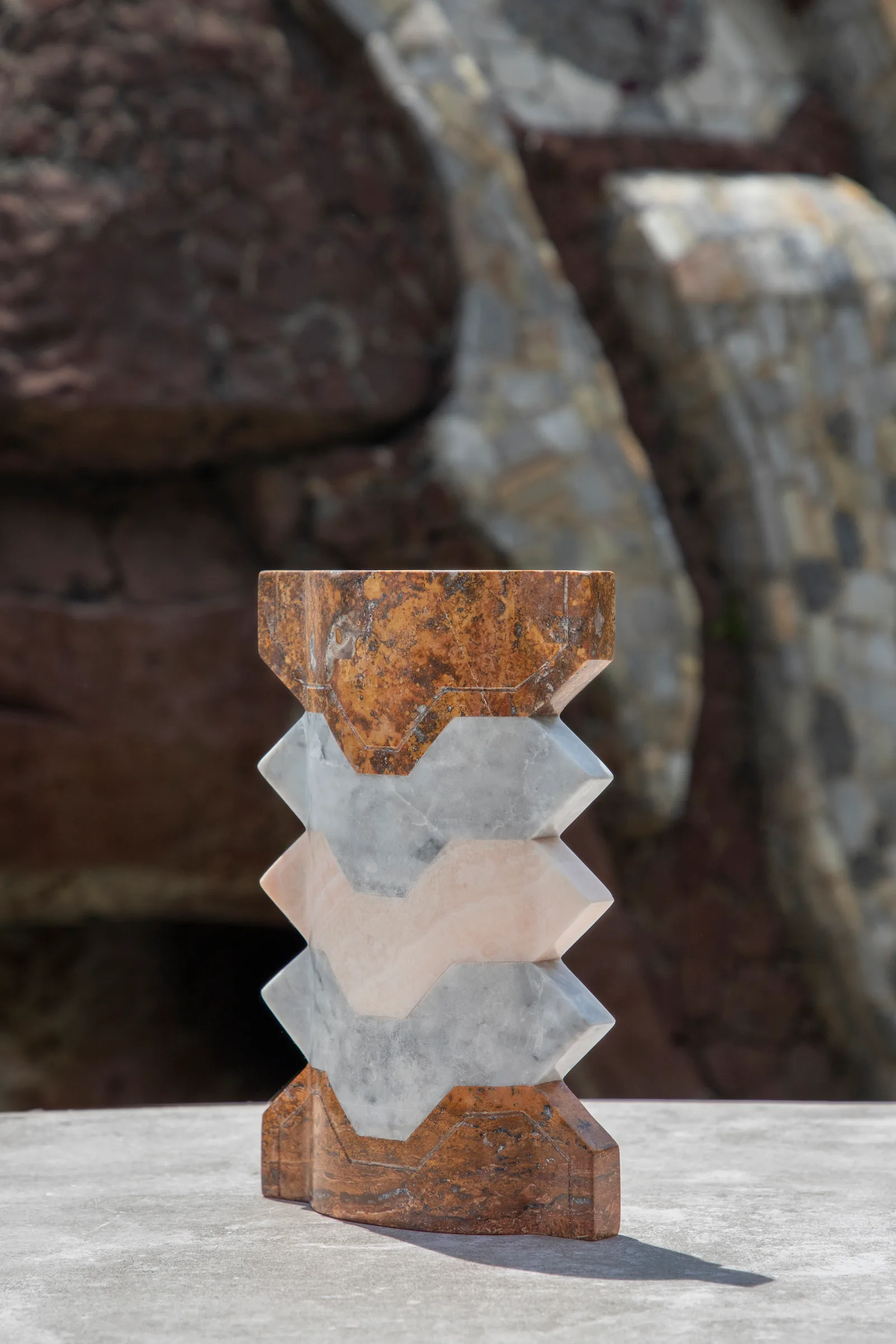 Místico III.II vase in red travertine, venetian marble, pink onyx — studio view
