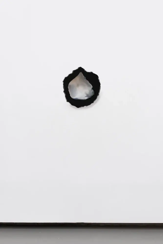 Silvered obsidian mirror sculpture on white gallery wall — poetic reuse of materials, waste-inspired art