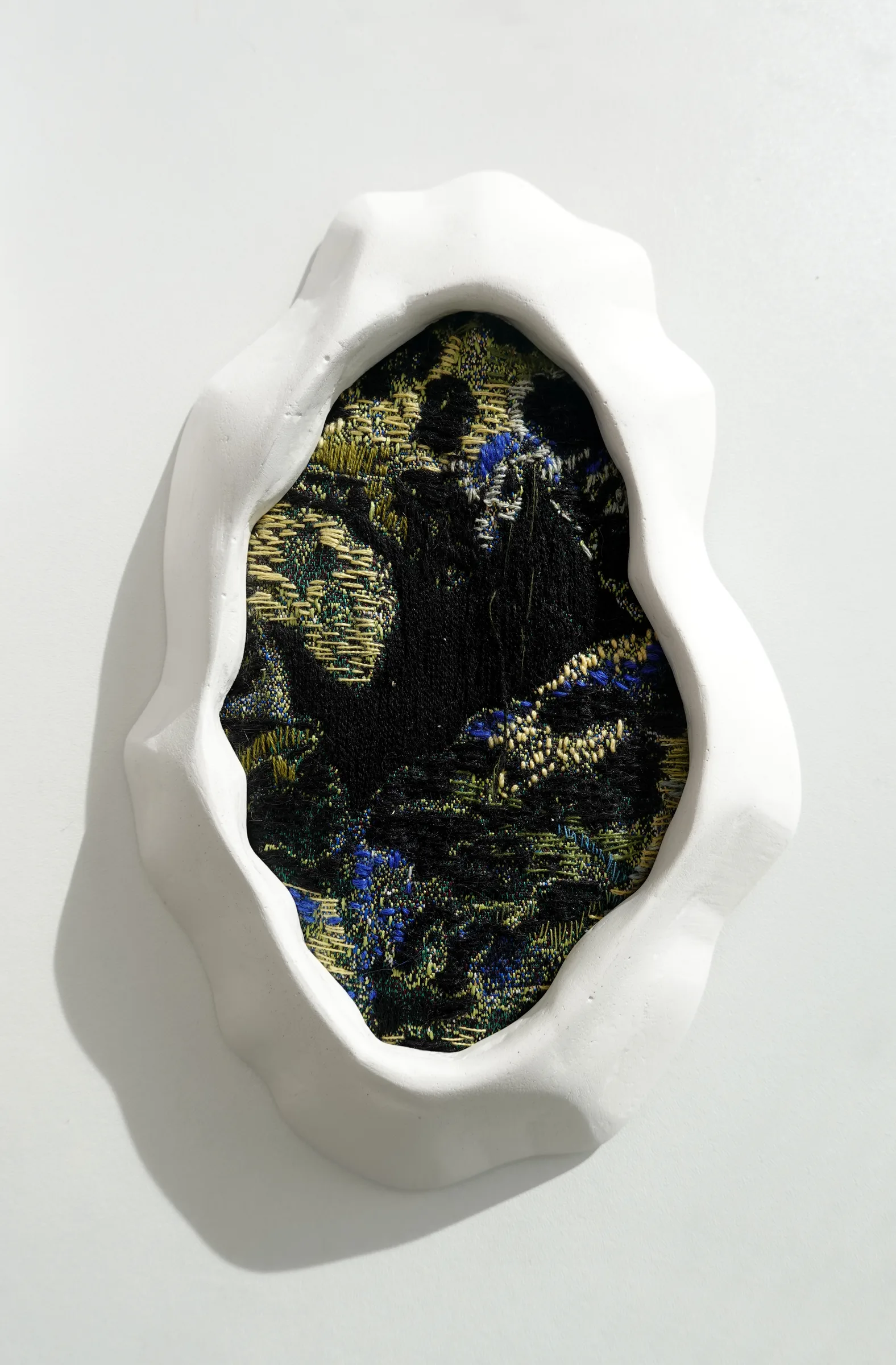 Memories 01, textil bordado en un marco de yeso blanco — vista de estudio