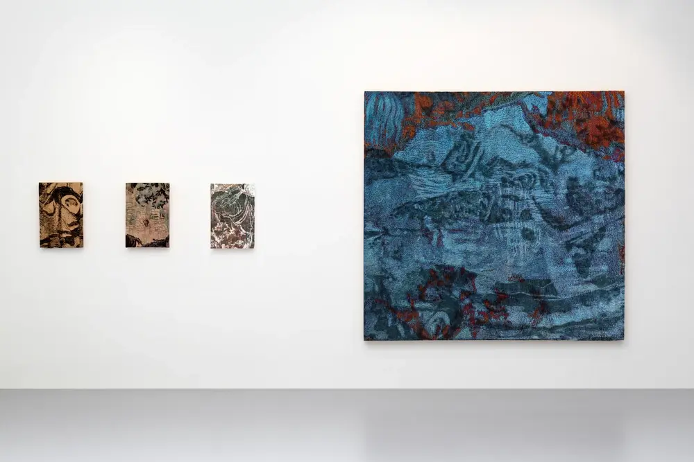 Gallery view with small tapestry paintings and large blue embroidered landscape