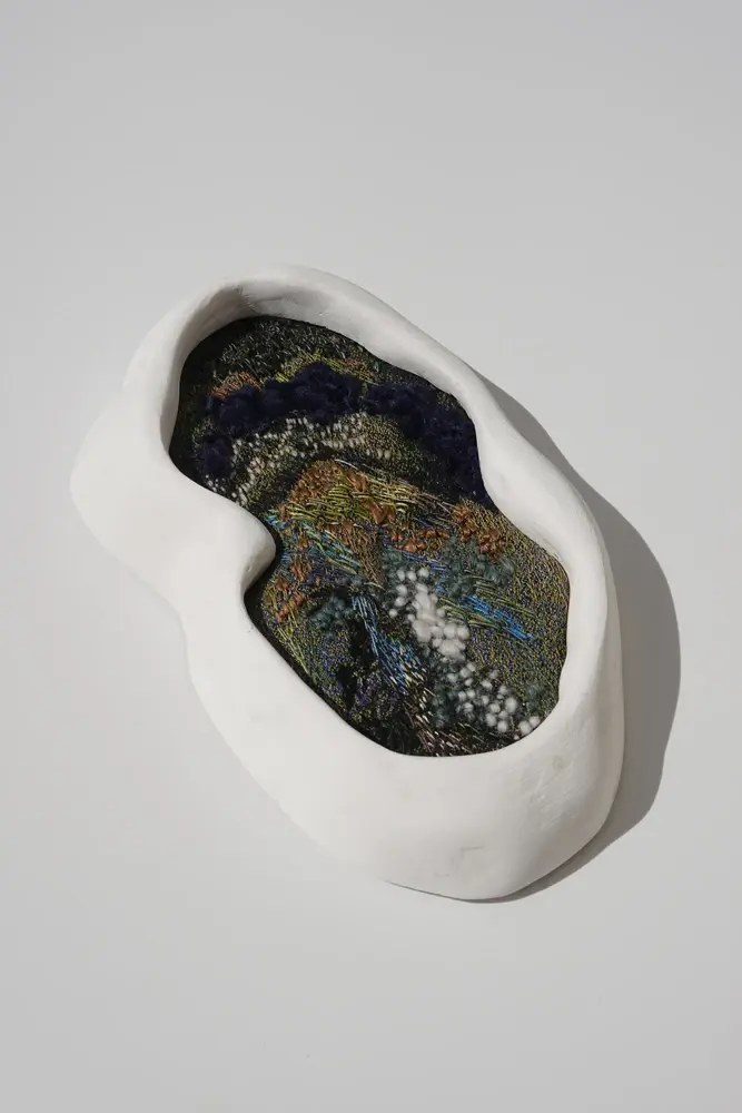 Sculpted ceramic form with embedded embroidered textile landscape